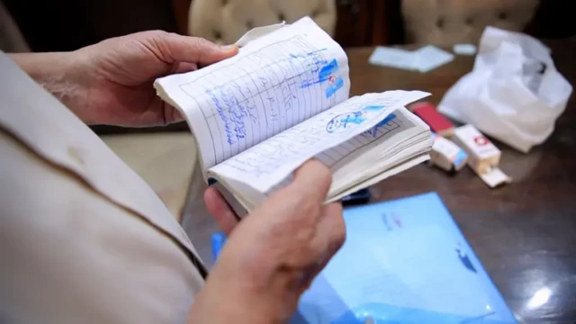 دستی دفترچه‌ای را گرفته که مهر و نوشته‌هایی با دست خط دیده می‌شود