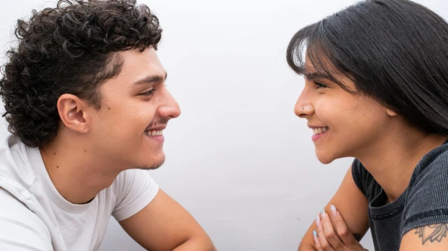 Um homem e uma mulher sorriem enquanto se olham nos olhos