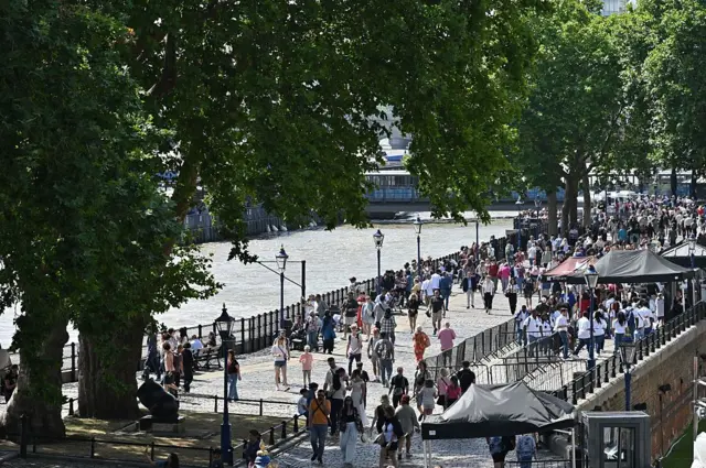 Ludzie spacerują wzdłuż Tower Wharf w upalny, słoneczny dzień
