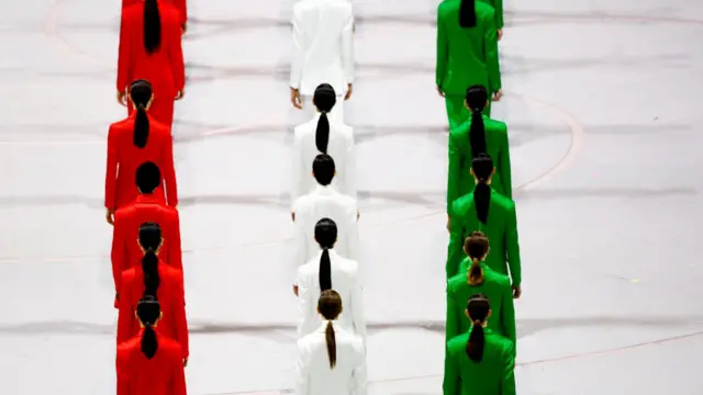 Модели, одетые в цвета итальянского флага идут по сцене на открытии Олимпиады 2026.