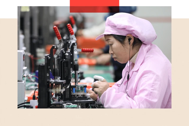 Una trabajadora de rasgos asiáticos, vestida de rosa una fábrica de chips.