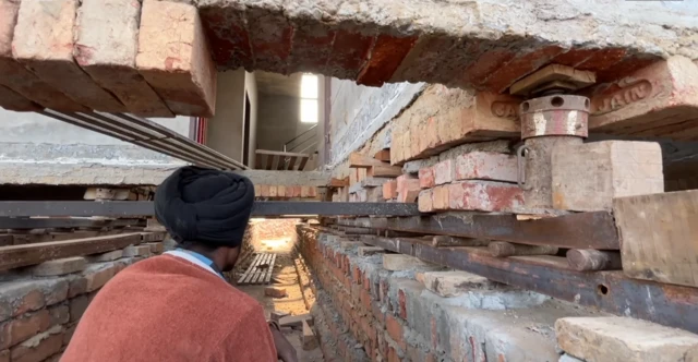 ਇੱਕ ਕਾਰੀਗਰ ਜੈੱਕਾਂ ਨੂੰ ਜਾਂਚਦਾ ਹੋਇਆ 