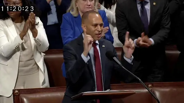 本会議場の演台に向かって立ち、長時間の演説を続けたジェフリーズ民主党院内総務。後ろでは民主党の同僚議員たちが立って拍手している