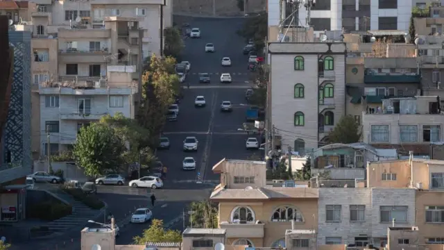 خودروها در امتداد یک خیابان به عنوان نمای ساختمان های مسکونی در شمال غرب تهران