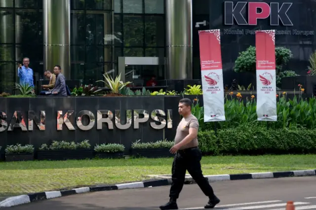 Seorang petugas polisi berpakaian preman berjalan melewati gedung Komisi Pemberantasan Korupsi (KPK) di Jakarta, pada 27 Juni 2023.