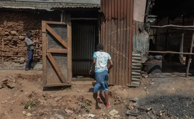 Une femme portant un bidon d'eau se rend dans un établissement public local pour y boire de l'eau.