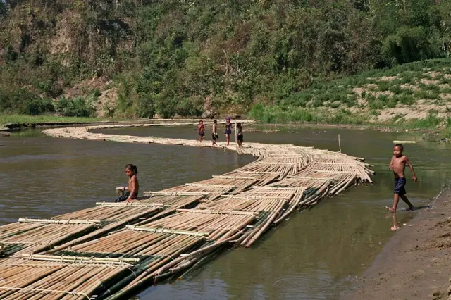 পাহাড়ি একটি নদীতে বাঁশ নিয়ে যাওয়া হচ্ছে