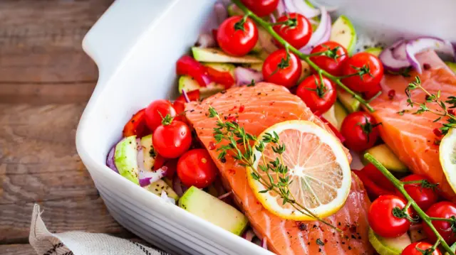 Bandeja com salmão, tomates, ervas e outras verduras, antes de ir ao forno