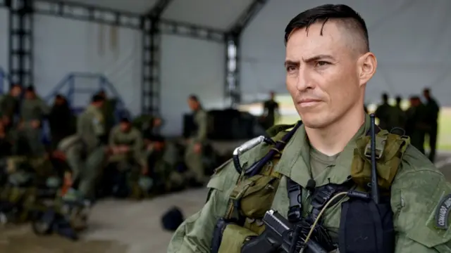 El mayor Cristhian Cedano habla con la BBC. Lleva el pelo corto y un uniforme verde. Tiene una pistola en una funda a la altura del pecho.