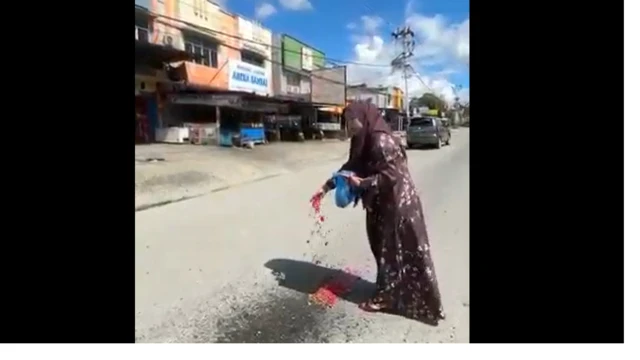 Ully sedang menabur bunga di lokasi kejadian insiden lalu lintas yang menewaskan putranya.