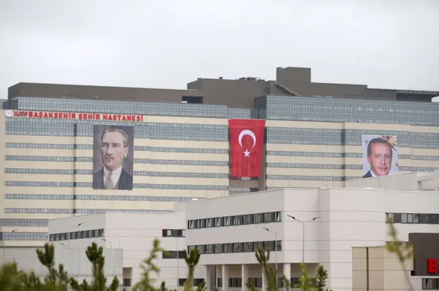 İstanbul'daki Başakşehir Çam Sakura Hastanesi. Yapının üzerinde Atatürk'ün ve Erdoğan'ın resimleri ile Türk bayrağı var.