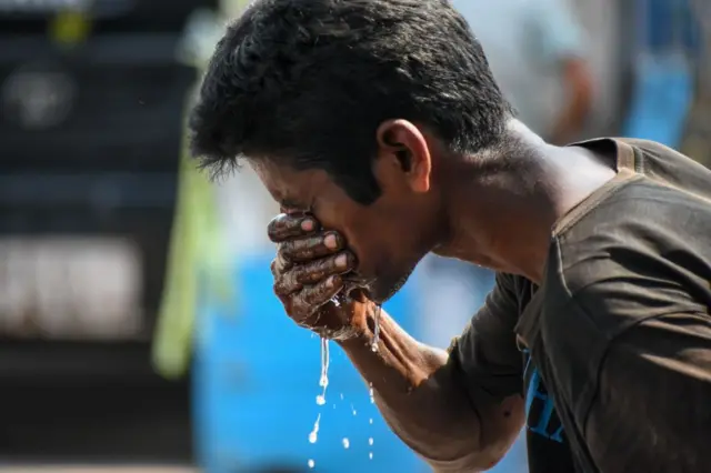 ఎండలో ముఖంపై నీళ్లు చల్లుకుంటున్న వ్యక్తి