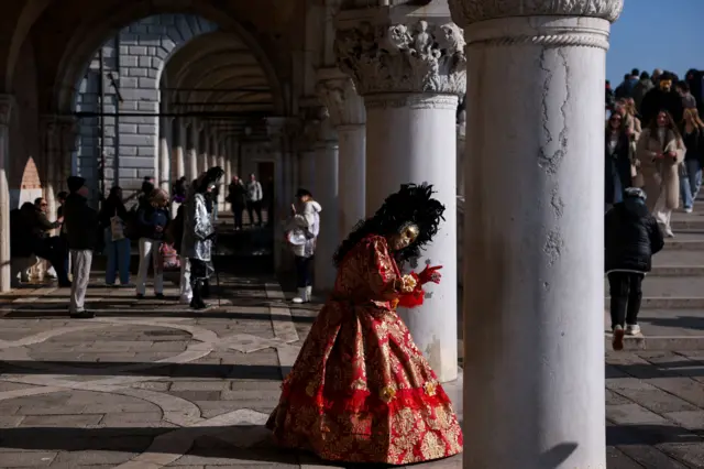 učesnica karnevala u Veneciji stoji pored stuba na Trgu svetog Marka, prvog dana Venecijanskog karnevala 