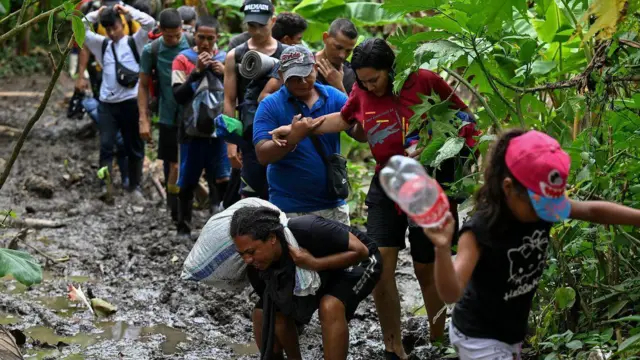 Grupo de migrantes caminha por trecho lodoso no Tampão de Darién