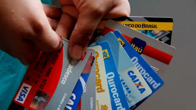 Mãos segurando diversos cartões de crédito