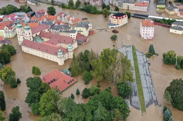 Imagem aérea mostra casas, árvores e rodovia parcialmente submersas