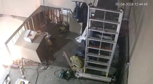 Yangının başlama anını gösteren CCTV görüntüsü. Sol tarafta yapılan kaynak işlemi ardından oluşan parlama görünüyor. Sağ tarafta dolaplar ve eşyalar var. 