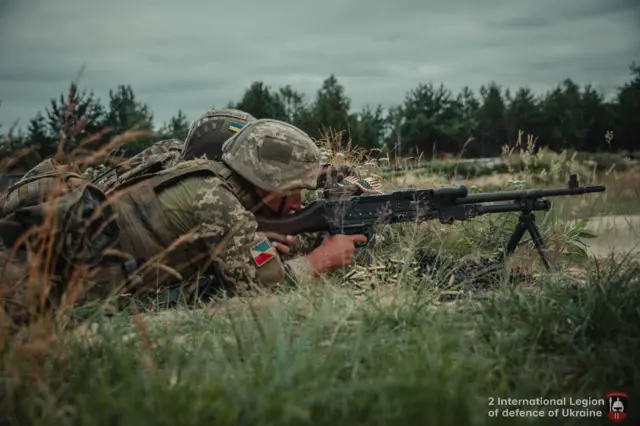 Двое военных стреляют из пулемета