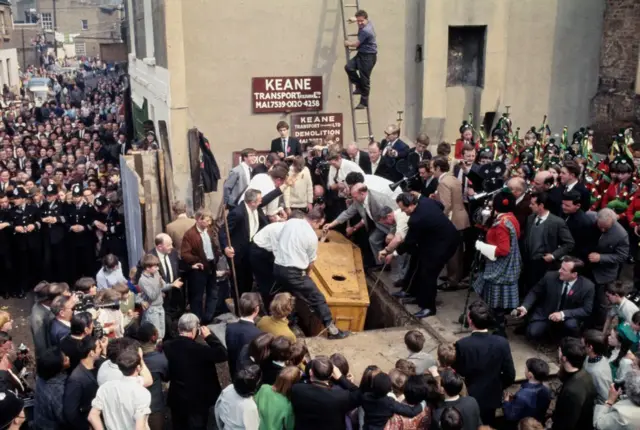 Momento en el que sacan el ataúd, con mucha gente alrededor
