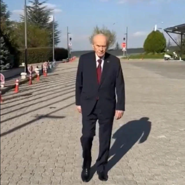 Koyu renk takım elbiseli Devlet Bahçeli yürüyüş yapıyor