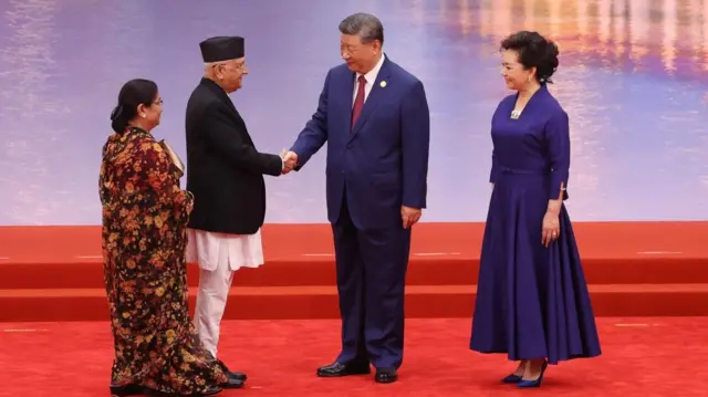 प्रधानमन्त्री केपी ओली चीनका राष्ट्रपति सी जिन्पिङसँग तियान्जिनमा हात मिलाउँदै। साथमा ओलीकी पत्नी राधिका शाक्य र सीकी पत्नी पनि छन् 