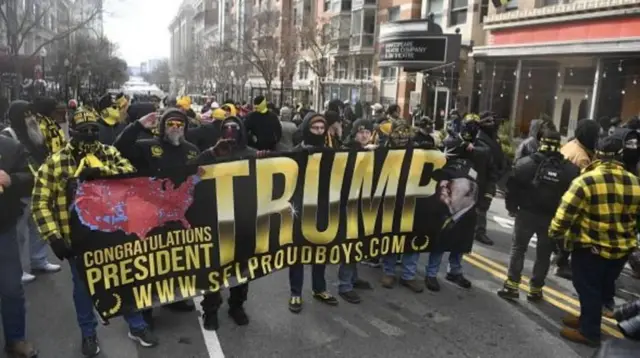 极右派的“骄傲男孩”（Proud Boys）组织成员在华盛顿的街道上游行。他们穿着标志性的黑色和黄色衬衫，手持支持特朗普的标语牌。该组织的数十名成员因参与1月6日美国国会大厦的骚乱而被监禁。