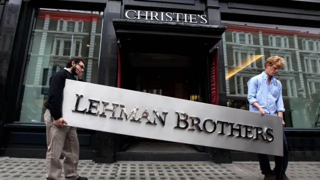 İki kişi Christie's'in önünde Lehman Brothers tabelasını tutuyor. 