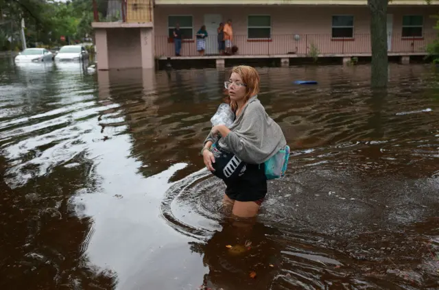 Makayla Richter atraviesa las aguas de la inundación después de tener que evacuar su casa en Tarpon Springs, Florida.