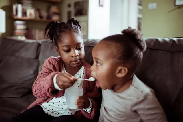fillette qui donne à manger à sa soeur