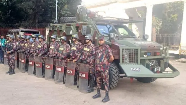 বিজিবি সদস্যরা দাঁড়িয়ে আছেন, পেছনে তাদের একটি এপিসি