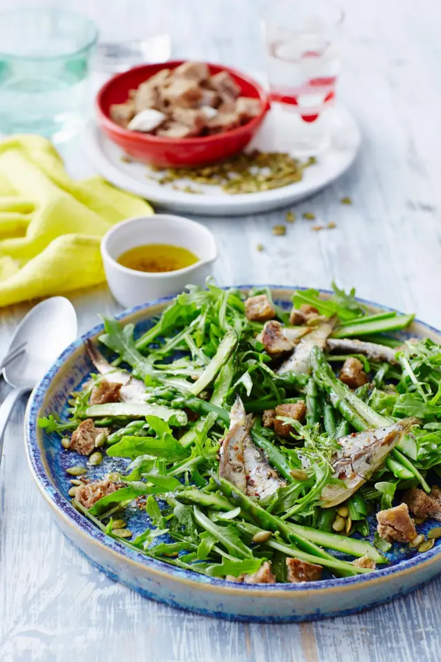 Salada com sardinhas e croutons, servida em um prato azul