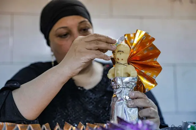 سيدة مصرية داخل مصنع بالعاصمة المصرية القاهرة، تزين حلوى عروس المولد( تمثال صغير مصنوع من السكر) والذي يأكله المصريون احتفالاً بمولد النبي محمد.