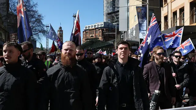 Участники марша протеста в черных одеждах с австралийскими флагами