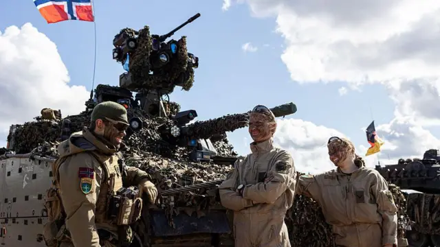 덴마크와 노르웨이의 나토군이 2025년 5월 훈련 중 탱크 앞에 서 있다