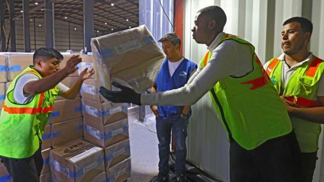 Trabajadores del Consejo Nacional Electoral trasladan las cajas con las papeletas electorales que se utilizarán este domingo.