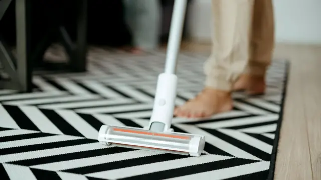 Жінка прибирає у вітальні вдома