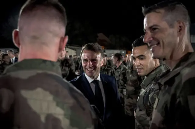 Le président français Emmanuel Macron regarde un dîner de Noël avec des soldats français préparé par les chefs de la présidence française à la base aérienne 188 "Colonel Massart" à Djibouti, le 20 décembre 2024, dans le cadre d'une visite de deux jours à Djibouti pour célébrer Noël avec les forces françaises déployées dans le pays dans le cadre du Traité de coopération en matière de défense (TCMD). 