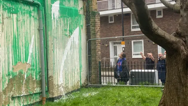 초록색으로 칠해진 벽화 위로 흩뿌려진 흰색 페인트