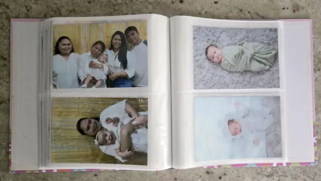 Un album foto care arată patru imagini. Două sunt cu un bebeluș, una cu copilul ținut în brațe de o femeie, iar alta cu copilul înconjurat de alte persoane din familie. 
