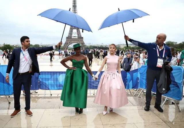 Sous les parapluies, Ariana Grande et Cynthia Erivo se tiennent la main à leur arrivée au Trocadéro.
