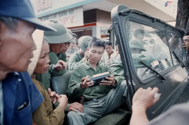 Một cán bộ đang xem xét chiếc radio trên đường phố Sài Gòn vừa được "giải phóng"