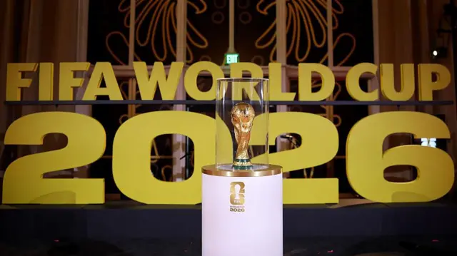 
Uma imagem do troféu da Copa do Mundo da FIFA diante das palavras “Fifa World Cup 2026”.
