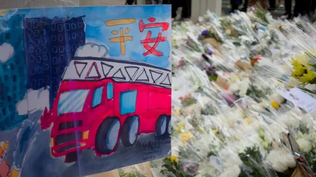 2025年11月30日，人们在香港大埔区宏福苑火灾现场附近摆放鲜花和画作，悼念这场致命火灾的罹难者。