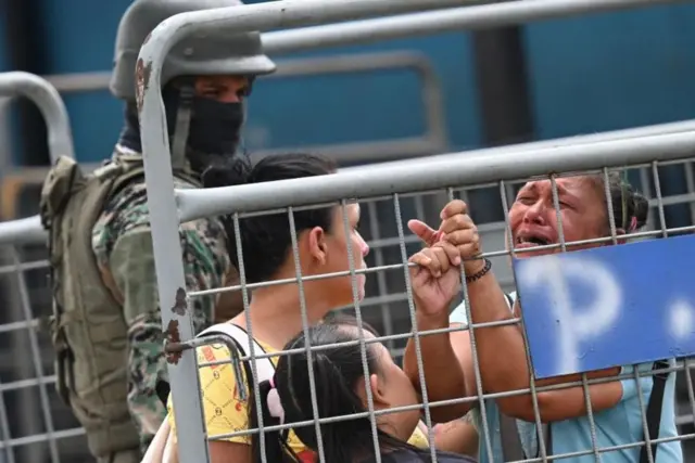 Mulheres chorando ao ladojogar na loteria federal pela internetgrades enquanto policial com balaclava as observa