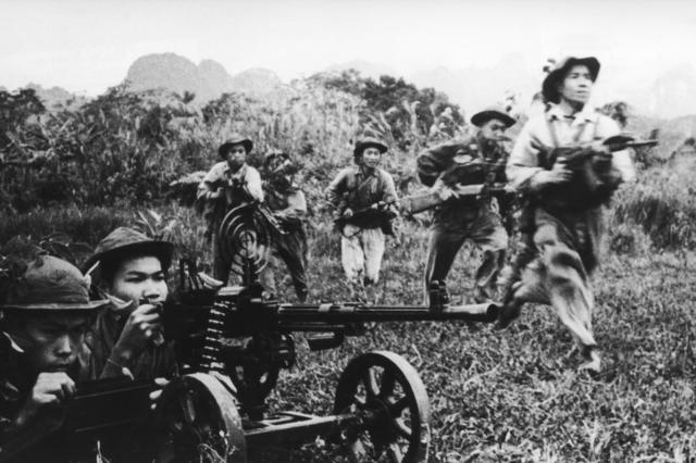 Soldados vietcongues avançando sob fogo de cobertura de uma metralhadora pesada durante a Guerra do Vietnã, por volta de 1968