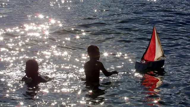 Enfants jouant avec un petit bateau en mer