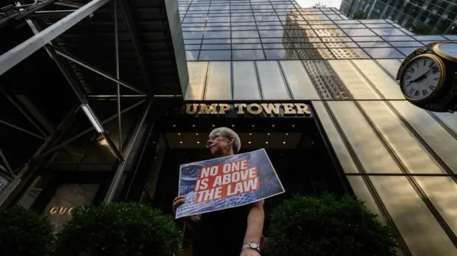 Trump Tower önünde "Hiç kimse hukukun üstünde değildir" yazılı bir döviz taşıyan Trump karşıtı