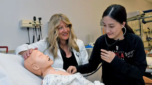 Dawn Mueller-Burke, left, a nurse practitioner and assistant professor at the University of Maryland School of Nursing, works with third-year student Anny Park, right, in the school's high-fidelity neonatal and pediatric simulation room on May 3, 2022.