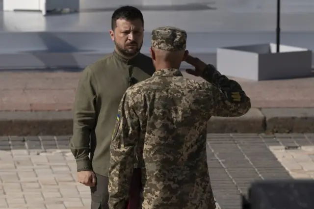 Soldado ucraniano de costas batendo continência para Zelensky