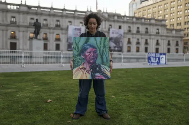 Una mujer posa con el retrato de Julia Chuñil al frente de la casa de gobierno en Santiago de Chile. 